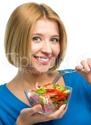 Young attractive woman is eating salad using fork