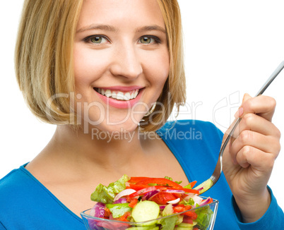 Young attractive woman is eating salad using fork