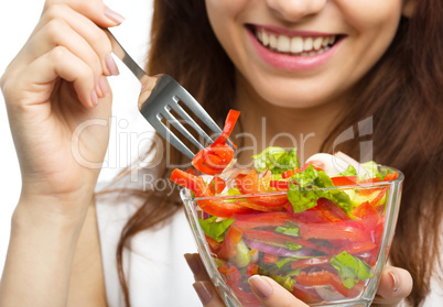 Young attractive woman is eating salad using fork