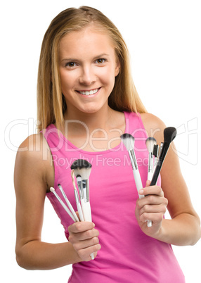 Teen girl is holding makeup brushes