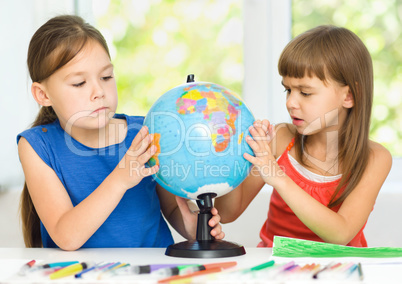 Little girls are examining globe