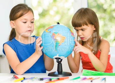 Little girls are examining globe