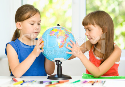 Little girls are examining globe