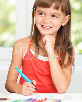 Little girl is drawing using pencils