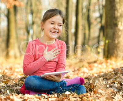 Little girl is reading a book outdoors