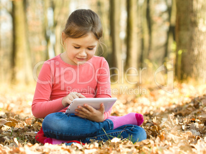 Little girl is reading from tablet