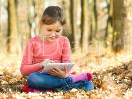 Little girl is reading from tablet