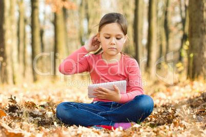 Little girl is reading a book outdoors