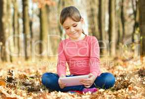 Little girl is reading from tablet