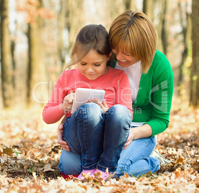 Mother is reading from tablet with her daughter