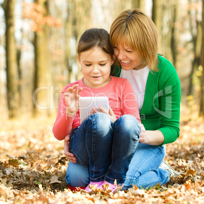 Mother and her daughter is playing with tablet