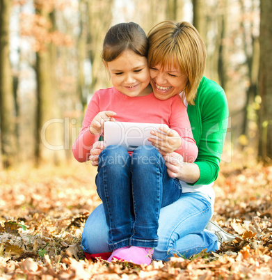 Mother and her daughter is playing with tablet