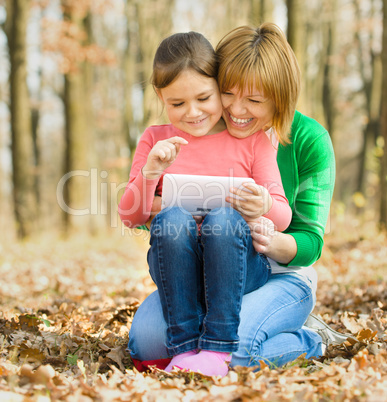 Mother and her daughter is playing with tablet