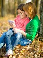 Mother and her daughter is playing with tablet