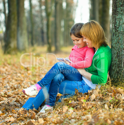 Mother is reading from tablet with her daughter