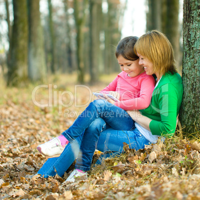 Mother and her daughter is playing with tablet