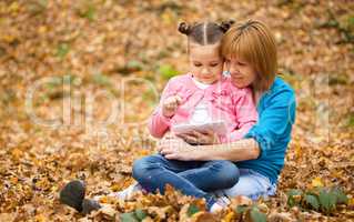Mother is reading from tablet with her daughter