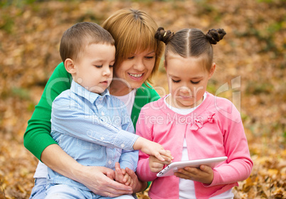 Mother is reading book with her daughter and son