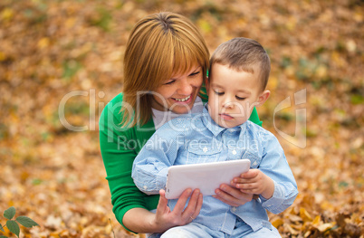 Mother is reading from tablet with her son