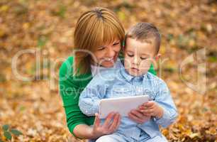 Mother is reading from tablet with her son