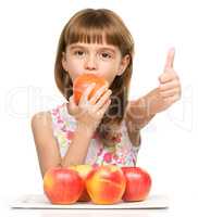 Little girl with apples is showing thumb up sign