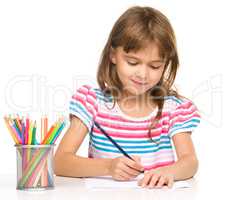 Little girl is drawing using pencils