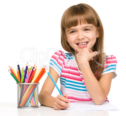 Little girl is drawing using pencils