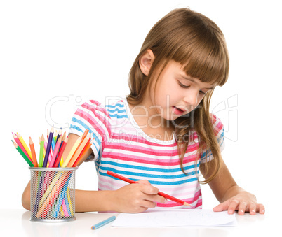 Little girl is drawing using pencils