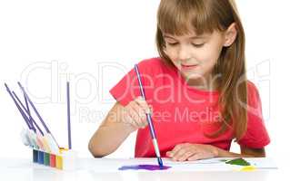 Little girl is painting with gouache