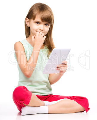 Young girl is using tablet while sitting on floor