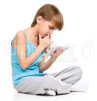 Young girl is using tablet while sitting on floor