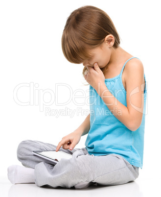 Young girl is using tablet while sitting on floor