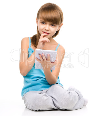 Young girl is using tablet while sitting on floor