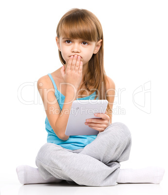 Young girl is using tablet while sitting on floor