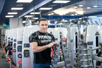 In gym. Muscular fitness trainer posing at camera