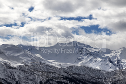 View on snowy mountains and cloudy sky in evening