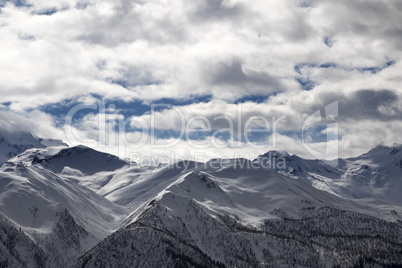 View on snowy mountains and cloudy sky in evening