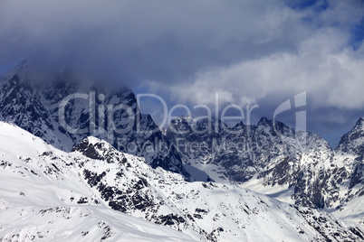 Snowy rocks in clouds at sunny day