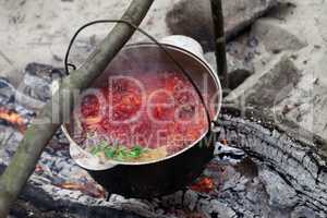 Borscht cooking in sooty cauldron on campfire