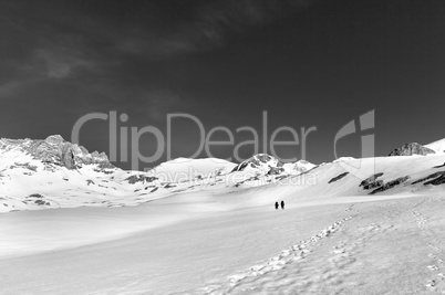 Two hikers on snow plateau (black and white)