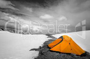 Orange tent in snow mountains. Selective color.