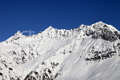 Snowy mountains and blue clear sky at sun day