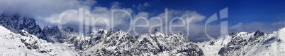 Large panoramic view on snowy mountains in haze at sunny day