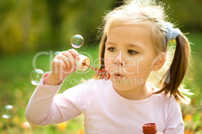 Little girl is blowing a soap bubbles