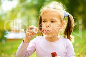 Little girl is blowing a soap bubbles