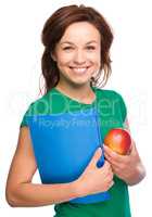 Young student girl is holding book and apple