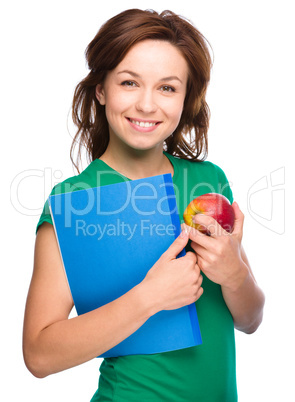 Young student girl is holding book and apple