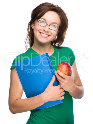 Young student girl is holding book and apple