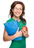 Young student girl is holding book and apple