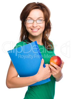 Young student girl is holding book and apple